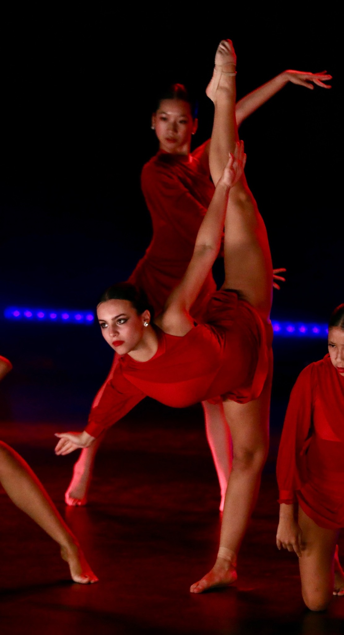 Bianca Papa performing with a dance ensemble under red stage lighting